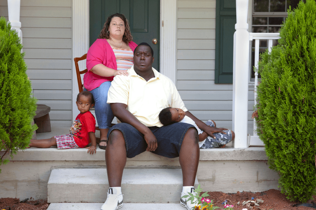 A family sitting on the stoop of their house
