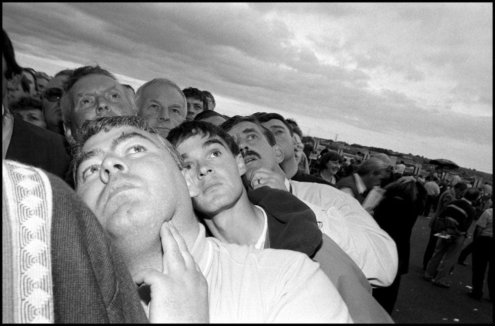 Black and white photograph of a group of men leaning left and looking up