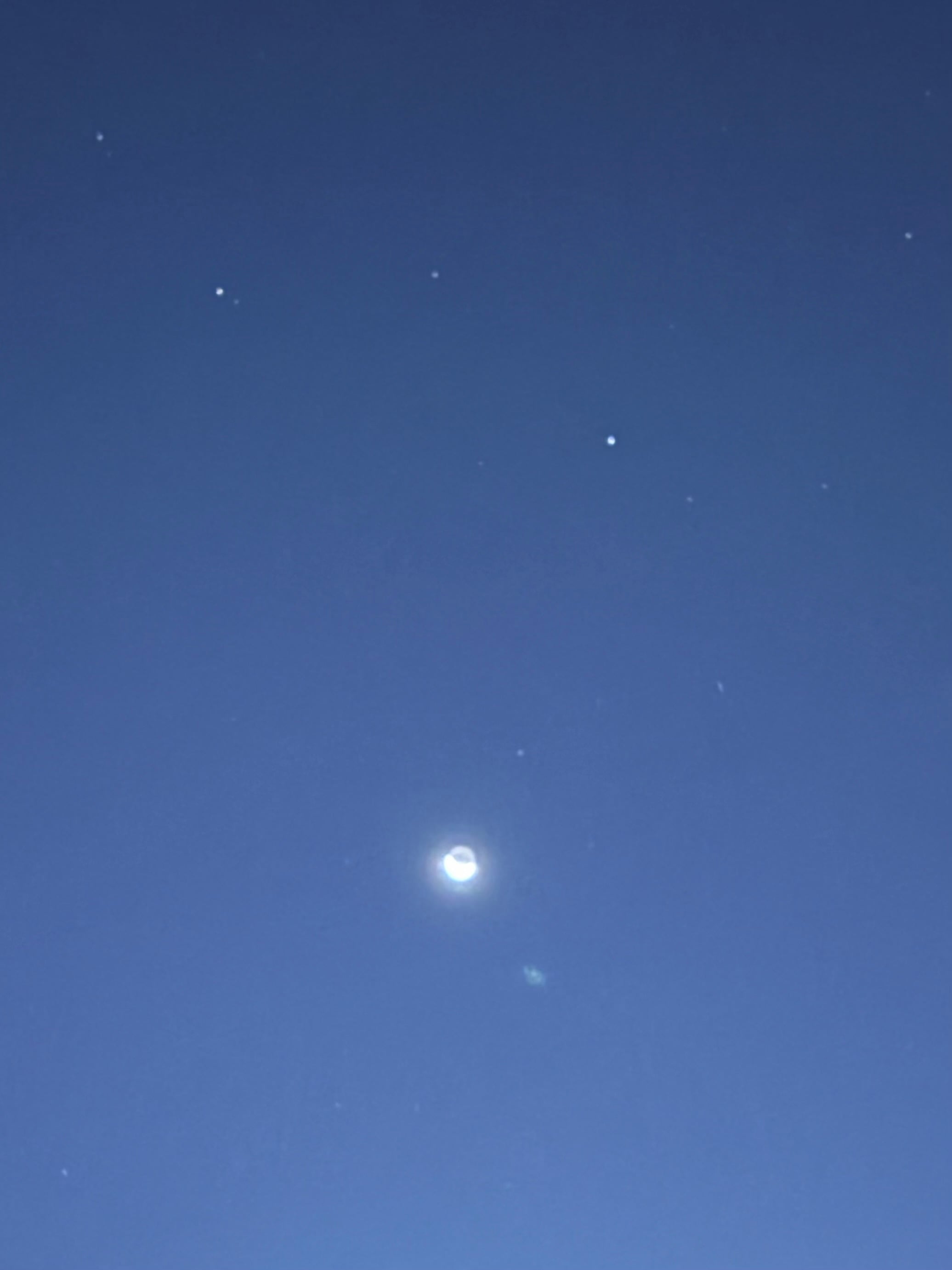 Slightly blurry photograph of the early morning night sky, showing the moon and a few stars